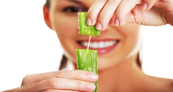 mujer sujeta una hoja de aloe partida donde se ve su jugo
