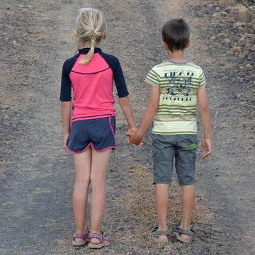 niña y niño de espaldas se cogen la mano