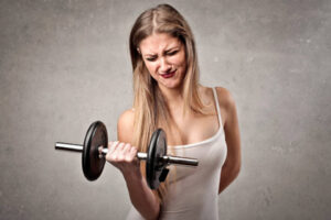 mujer entrenando biceps con cara de esfuerzo