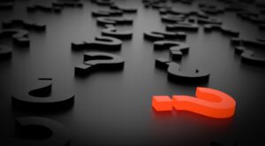 interrogantes negros en el suelo y uno rojo que destaca