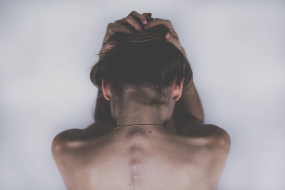 mujer de espalda desnuda manos en la cabeza, actitud depresiva