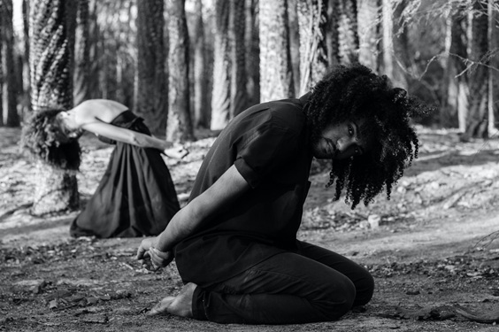 pareja arrodillada, distante, con manos atadas en un bosque