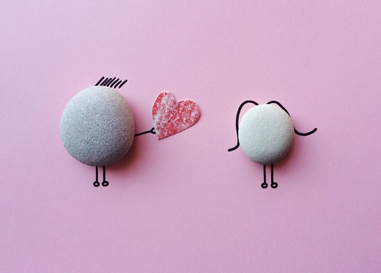piedras que simulan hombre que entrega un corazón de papel a mujer