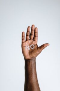 palma de mano de afroamericano con escrita blanca: 'no'