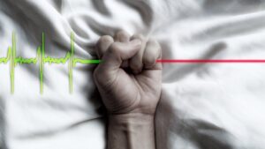 puño bloqueando la línea de los latidos del corazón de un electro cardiograma-imagen simbólica