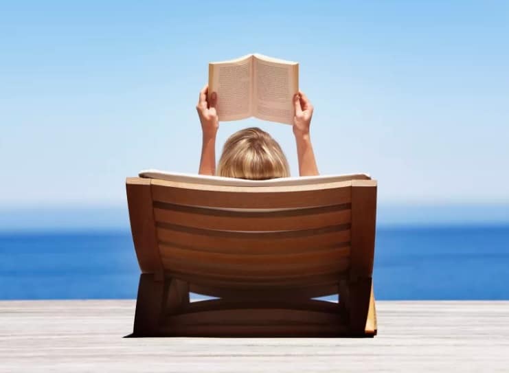 tumbona de madera con mujer leyendo libro