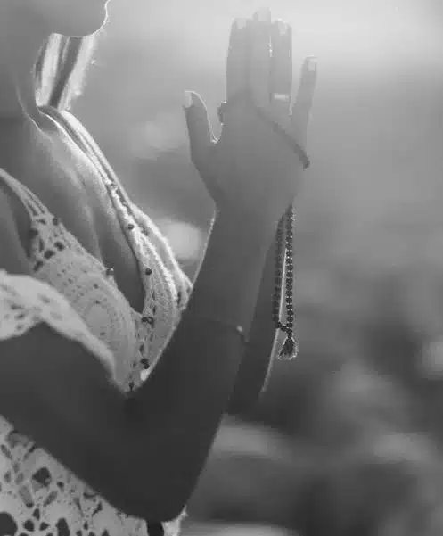 manos de mujer rezando con mala entre las manos